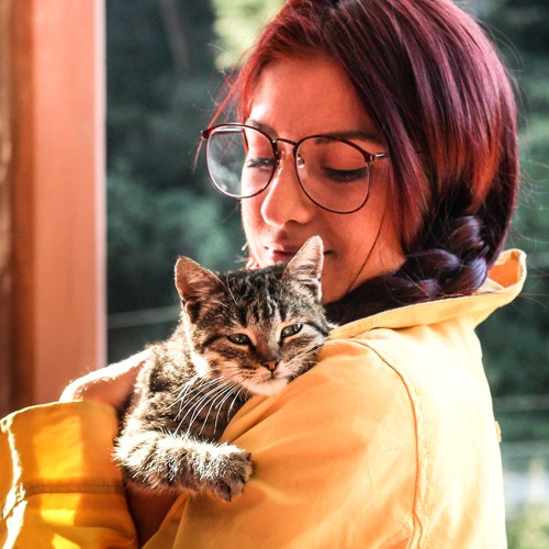 Woman  in a yellow coat holding a furry kitty